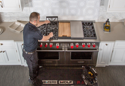 clarke customer care technician servicing a wolf range oven in a modern white kitchen