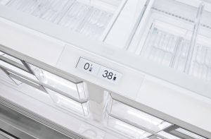 A digital display on this Sub-Zero refrigerator shows the freezer at 0°F and the refrigerator at 38°F, with empty, clear storage drawers visible.