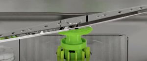 Close-up of a Cove dishwasher’s interior shows a rotating spray arm mounted on a green central hub, highlighting this innovative kitchen appliance.